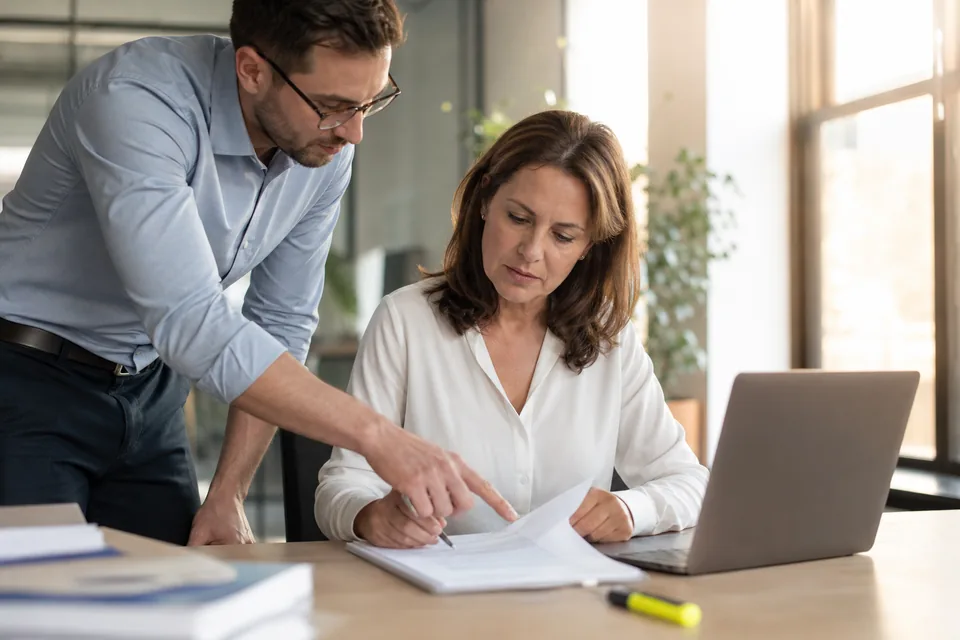 Head of people marking clauses on a printed recruiter fee agreement at her desk