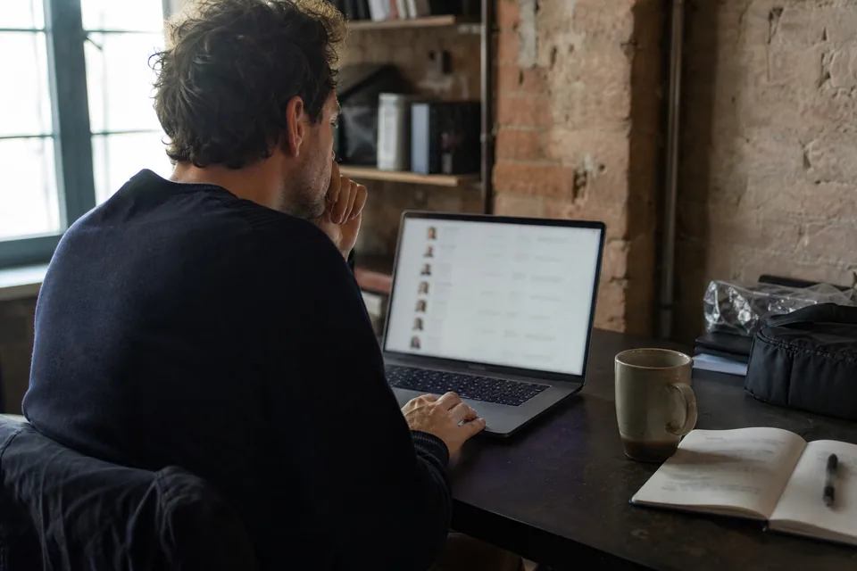 Startup founder sourcing marketing candidates on a laptop in a shared office